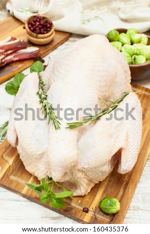 Whole raw  turkey on wooden cutting board,vegetables, ham and  spices. Viewed from above