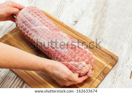 Stuffed Veal Roulade,  tied up with rope , ready to barbecue. Raw rolled meat enclosed in tied netting. Copy space composition. Viewed from above