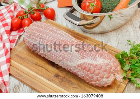 Raw rolled meat. Stuffed Veal Roulade on wooden cutting board. Uncooked meat. Raw fresh veal  roulade ready to cooking Raw rolled meat enclosed in tied netting.