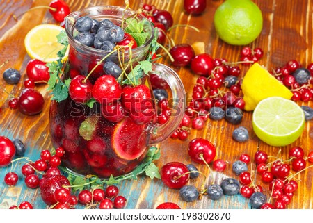 Sangria Fruit Punch. Refreshing fruit punch beverage in pitcher over rustic wooden background.