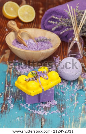 Lavender and lemon aromatherapy. Natural handmade lavender oil, soaps with bath salt,  foaming bath bomb, lemon and lavender on wooden background. Macro, selective focus.