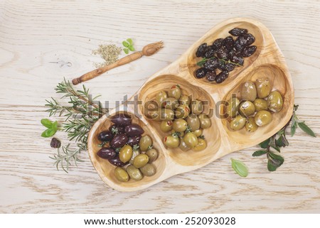 Assorted types of olives. Variety of green, black and mixed marinated olives in olive tree dish on wooden table