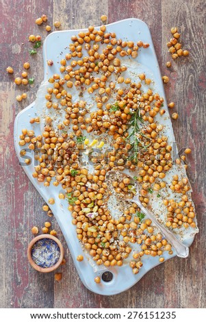 Spiced chickpeas. Spicy Oven Roasted Chickpeas on a wooden board, rustic  wooden background, vintage style.  Natural light