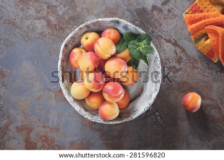 Apricots. Bowl of harvested apricots on a rustic stone surface, top view, rustic style. Natural light