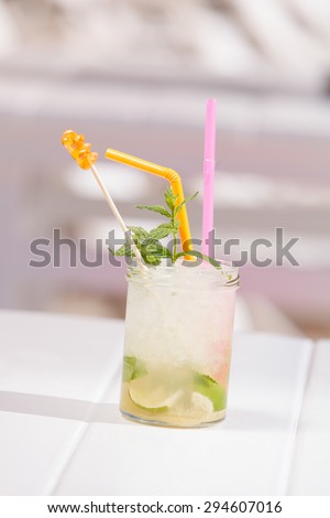 A jar of mojito cocktail with ice and a straw  at a beach bar. Selective focus