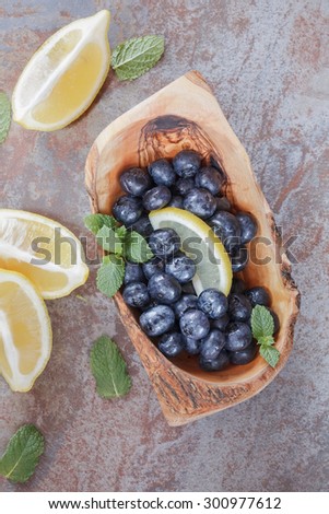 Blueberries in bowl  on  rustic  table. Fresh Blueberries  and lemon slice on  table, vintage style. Macro, selective focus. Natural light