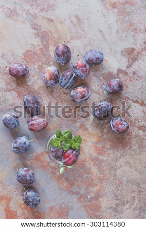 Freshly picked organic plums  in jar and on rustic table. Vintage style, top view