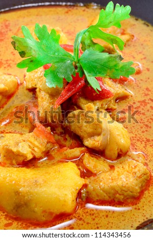 MUSLIM CURRY WITH CHICKEN TOPPING WITH PARSLEY AND CHILI IN BLACK BOWL