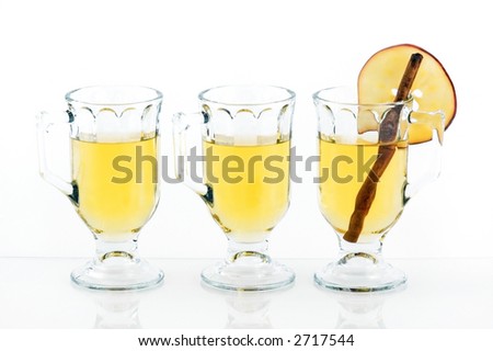 Line of glasses of apple cider - right glass contains cinnamon stick and apple slice on rim
