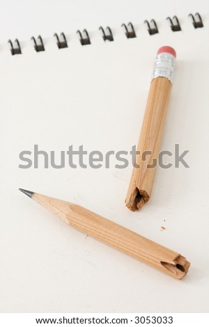 Broken pencil lies on white pad - spiral binding out of focus in background