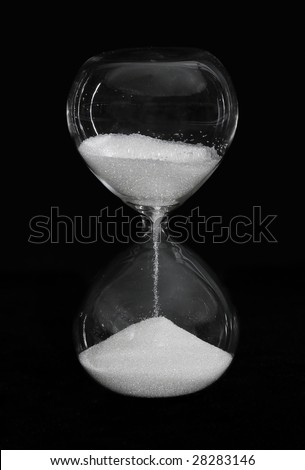 Time Passes - Glass hourglass with white sand on black