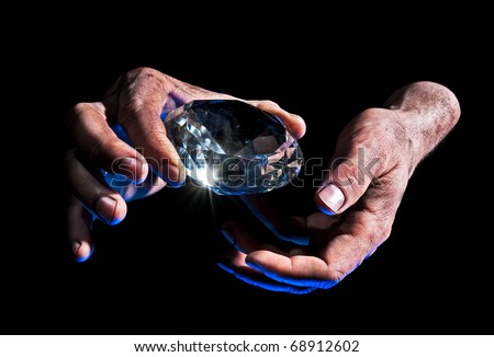 Presenting Diamond - Dirty male hand hold diamond against black background - blue lit from underside