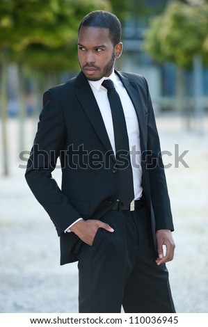 Handsome young African American business man in a black suit outdoors.