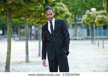 Horizontal portrait of a young handsome African American business man posing outdoors in a suit.