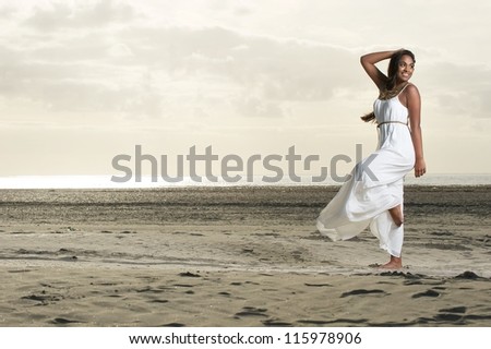Beautiful African American woman doing dance pose with a smile at the beach.