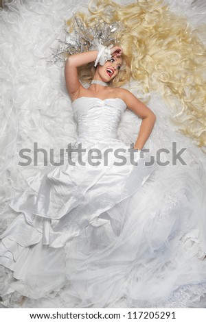 Portrait of a smiling bride lying on a cloud of white lace fabric