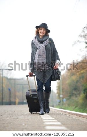 Portrait of a older woman walking on train platform with bag