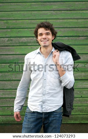 Handsome guy holding his jacket over his shoulder outdoor.  Smile expression on his Face.