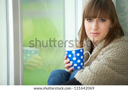 Close up portrait of a young woman relaxing by window with cup of tea