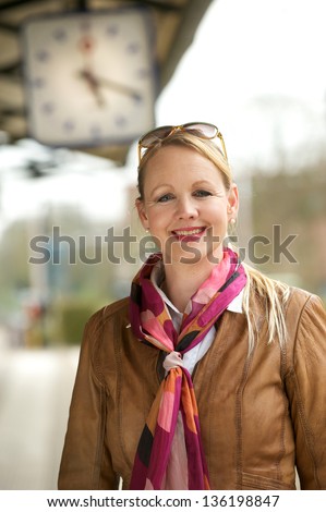 Close up portrait of a beautiful older woman smiling under train station clock outdoors