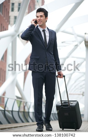 Portrait of a young businessman walking and talking on the phone at metro station