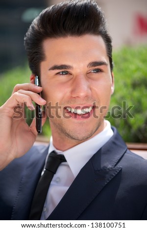 Portrait of a handsome young businessman talking on the phone outside the office