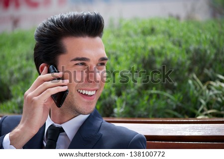 Close up portrait of a happy businessman talking on the phone outside the office