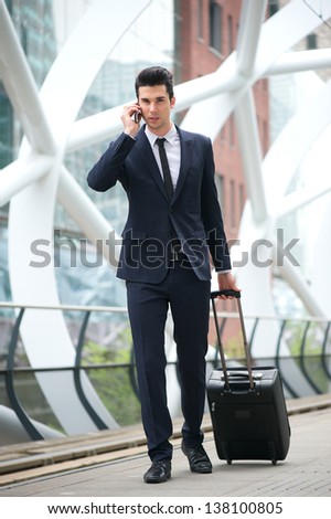 Portrait of a young businessman calling on phone and traveling with bag at metro station