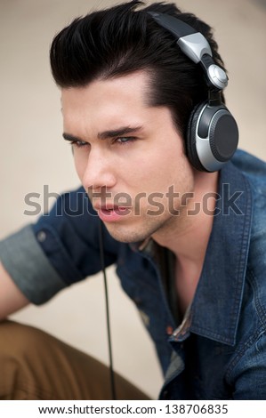 Portrait of an attractive man listening to music on headphones outdoors