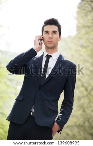 Portrait of a young businessman talking on phone outside the office