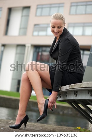 Portrait of a young business woman adjust her shoes outdoors