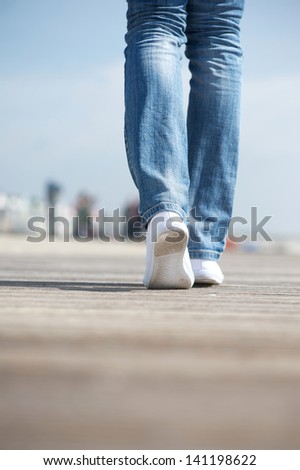 Rear view portrait of a woman walking in blue jeans and comfortable white shoes