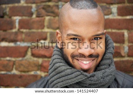 Close up portrait of a happy african american man smiling with scarf outdoors