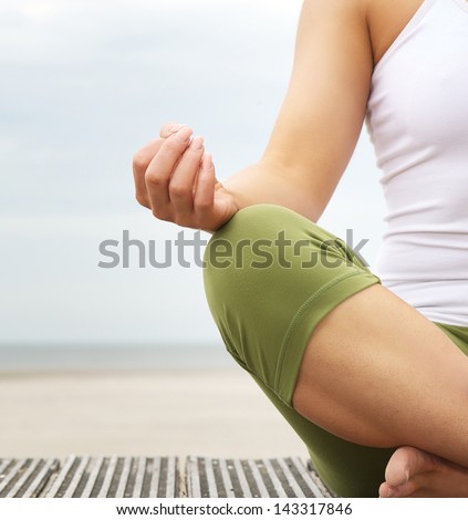 Close Up Portrait Of A Young Woman In Lotus Position With Yoga Hands At The Beach