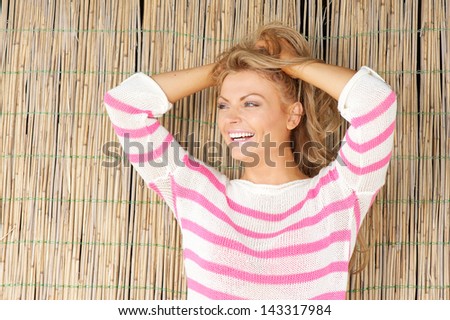 Close up portrait of a beautiful young woman laughing with hands in hair