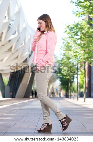 Profile portrait of a beautiful young woman talking on mobile phone in the city