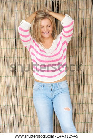 Portrait of a beautiful blond woman laughing with hands in hair