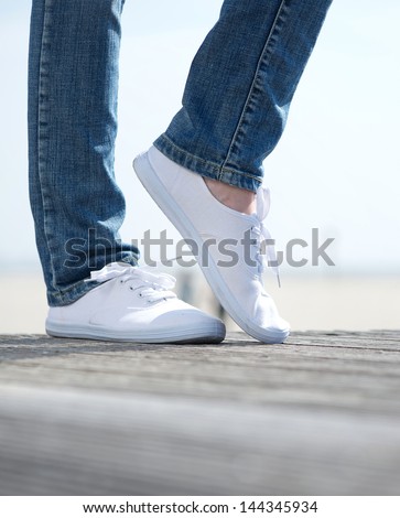 Pair of woman legs in comfortable white shoes standing outdoors