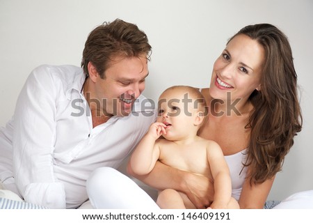Portrait of a happy mother and father hugging baby