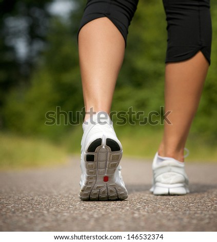 Female walking on path in running shoes from behind