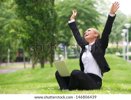 Portrait of a successful  businesswoman with laptop and arms outstretched