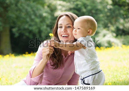Portrait of a happy mother and child holding flower in the park