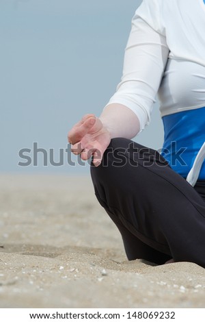 Closeup of woman hand in lotus yoga pose at the beach