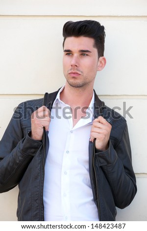 Closeup portrait of an attractive male fashion model holding black leather jacket