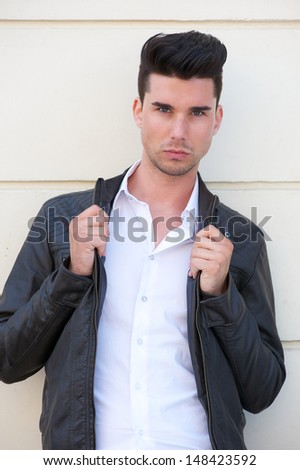 Closeup portrait of a handsome young man holding black leather jacket