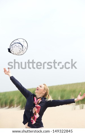 Portrait of a carefree older woman throwing hat up with outstretched arms