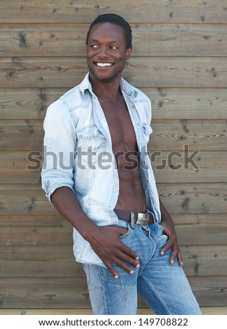 Portrait of a happy young black man smiling outdoors with open shirt
