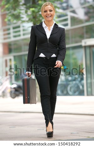 Full length portrait of a business woman walking in the city with briefcase