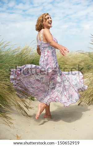 Portrait of a beautiful older woman with flowing dress at the beach