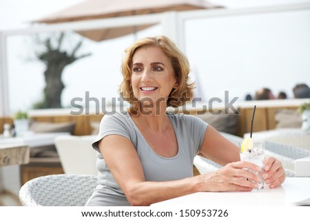 Horizontal portrait of a happy woman relaxing with a drink of water at outdoors restaurant